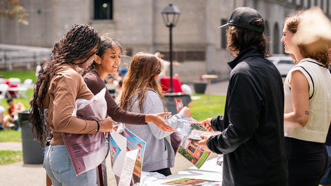Students from the Class of 2028 collect flyers and posters from staff at the Athletics complex.