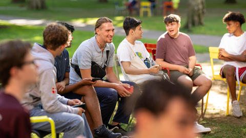 Students in the Yard during summer engage in conversation on lawn chairs.