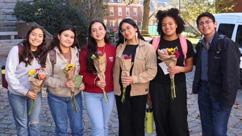 Students pose with a bouquet of flowers at the flower truck in front of Boylston Hall as part of first-gen, low income visibility week