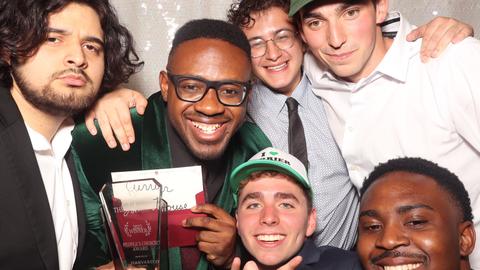 Students from Currier House pose for a photo in a photo booth with their award after winning a Johnnie.