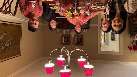 one host and four students sit around a dining room table smiling