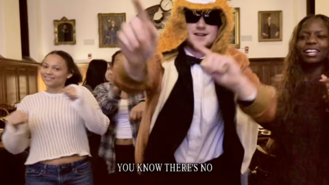 A snapshot of the Winthrop House Housing Day video with a student in a lion costume walking through the House with other students behind them.