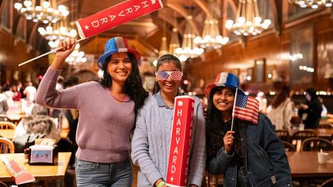Three students in Annenberg dining hall in election night gear during the 2024 presidential elections watch party.