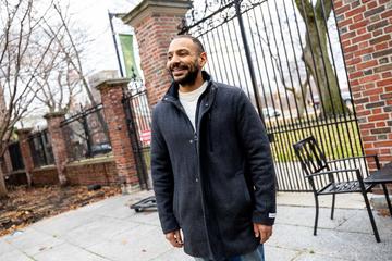 Julian Hayes, tutor at Leverett House smiles as he looks out into the distance in the Leverett House courtyard.