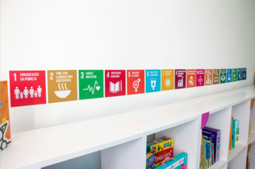 Various color icon graphics lined up on a wall right above a white book shelf containing books and games.