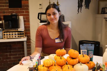 Students smiles for a photo before she begins painting miniature pumpkins for Foundation Fridays.