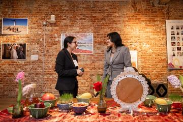 Two students interact over an ornately-set table.