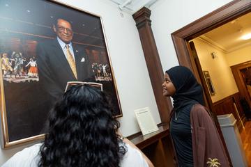 Students gaze up at a portrait hung on the wall as part of the portraiture project sponsored by the Harvard Foundation.