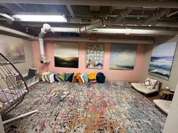 The Kirkland meditation space with rugs, floor pillows, floor seats, a swing seat, and landscape paintings on the wall.