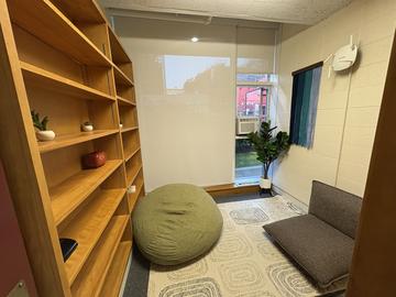 Quincy House meditation space with built-in bookshelving, bean bag, floor seat, rug, and plant.