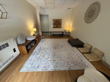 The Currier House meditation space with floor seats, a rug, and simple wall decor.