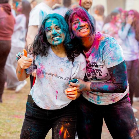 Students covered in colored powder pose for a photo after the Dharma Holi celebration in Harvard Yard.