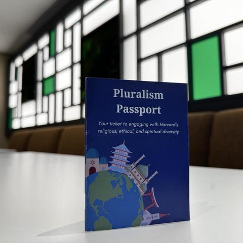 The Harvard pluralism passport propped up on a table in front of stain glass windows.