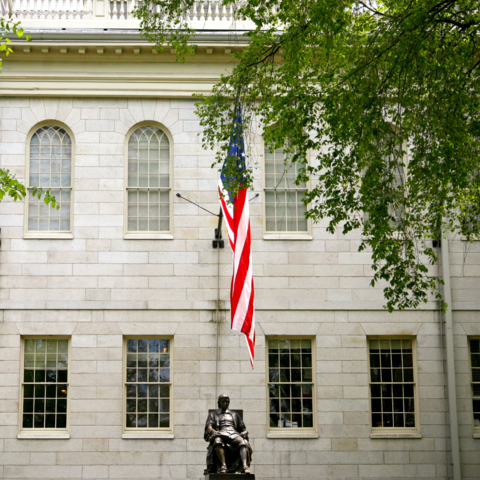 University Hall in the summer from the front view with the American flag above.