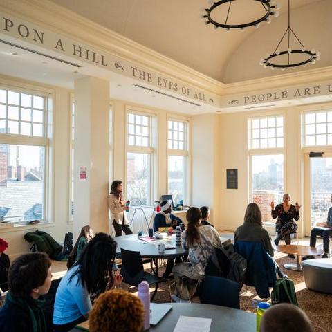 Students in the Beren Rooftop Room in Winthrop House listening to speakers discuss sustainability.
