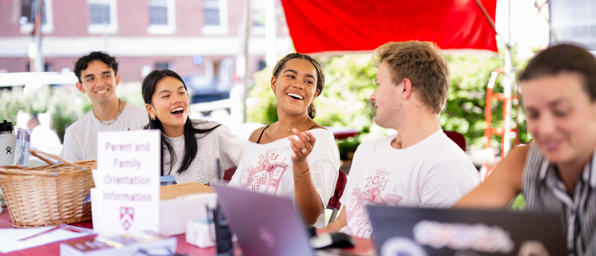Students laugh and talk volunteering at the Welcome tent at first-year move-in.