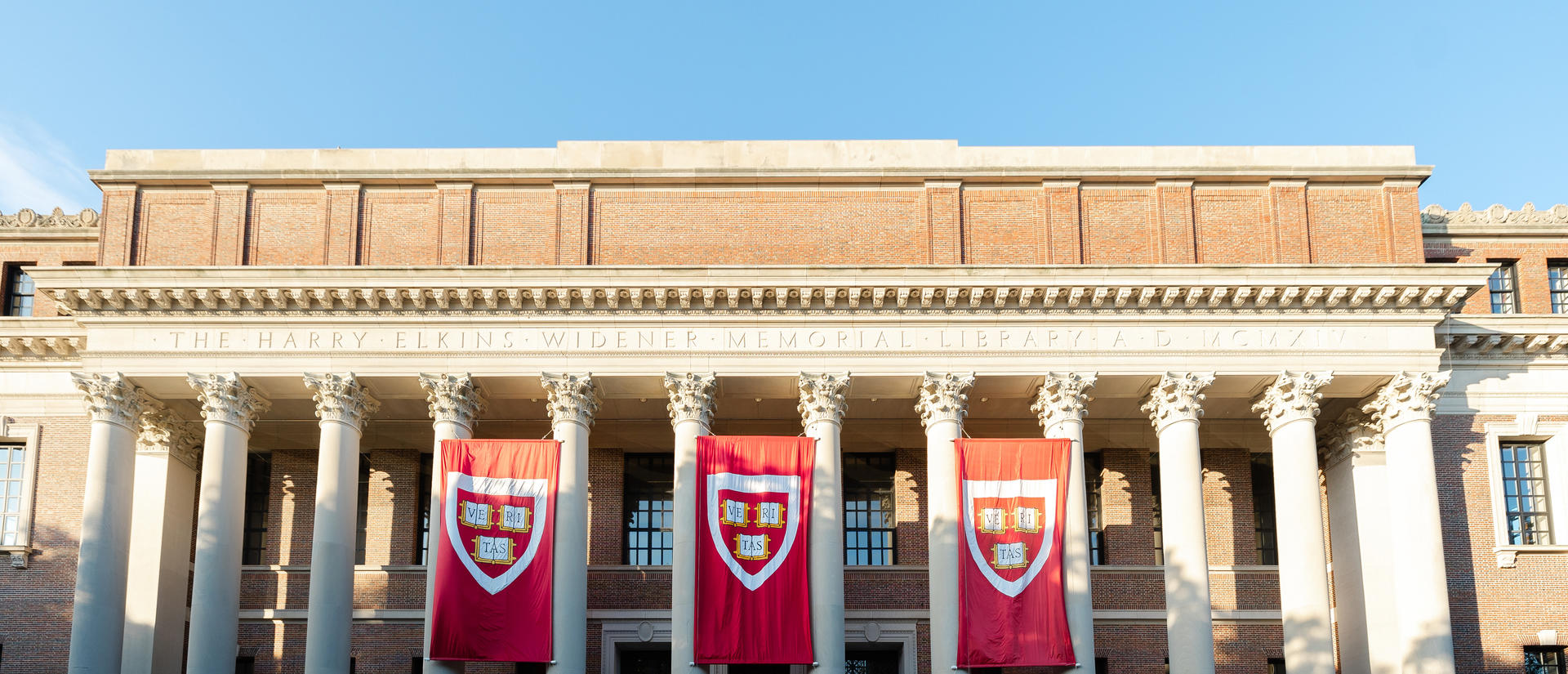 Harvard University crimson banners hanging between the columns of Widener Library on Commencement Day.