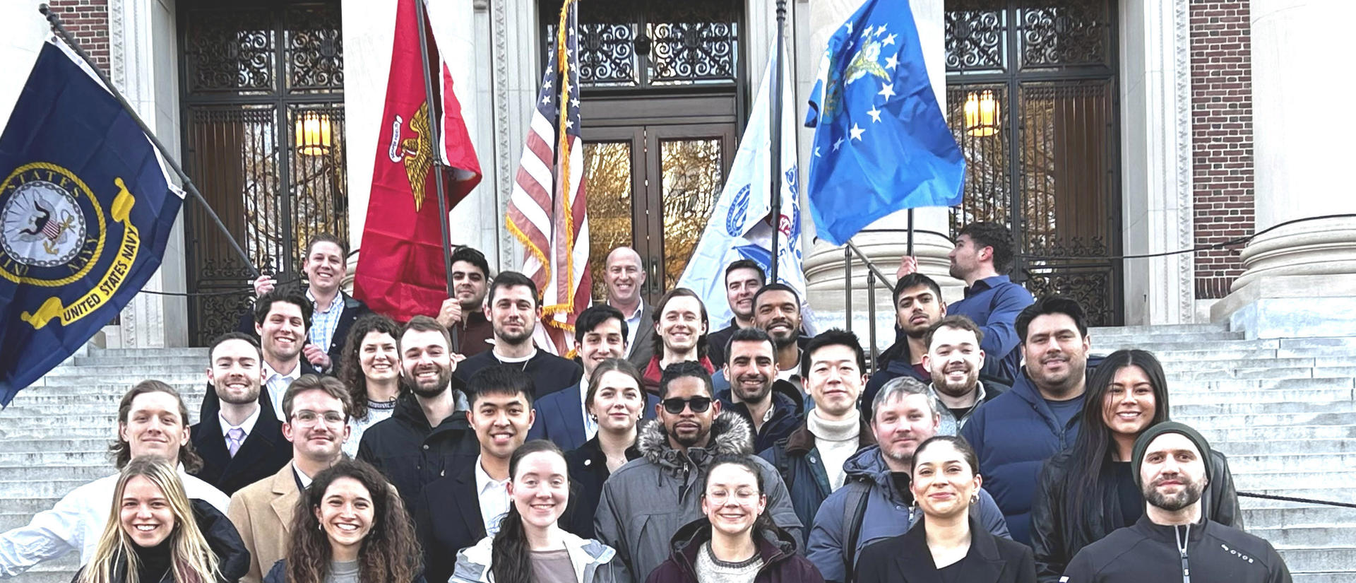 Students veterans on the steps of Widener Library with flags in the background.