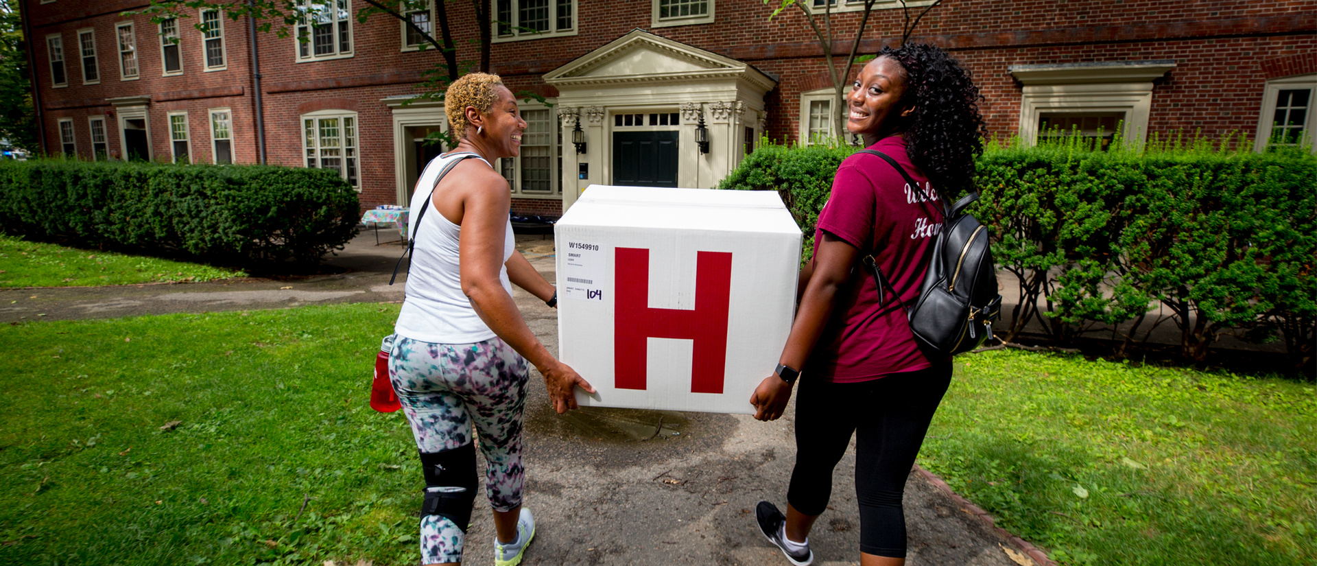 Students carrying move-in box with Harvard H
