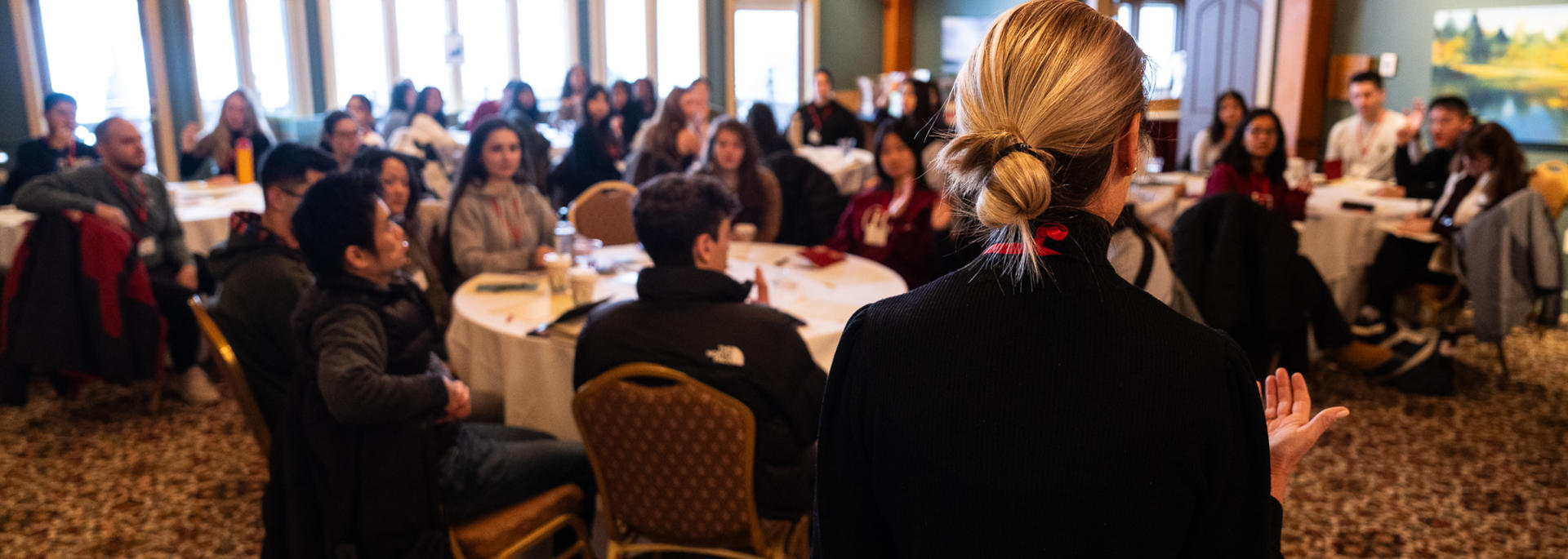 Students at round tables hearing from Jenni Wallace at the Mattering Retreat.