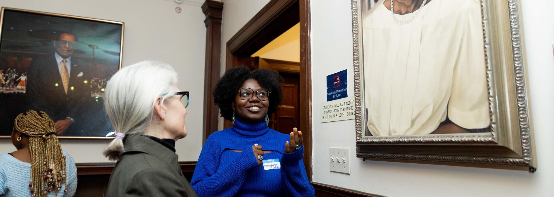 A staff member discusses a portrait with a student during a Harvard Foundation portraiture event.