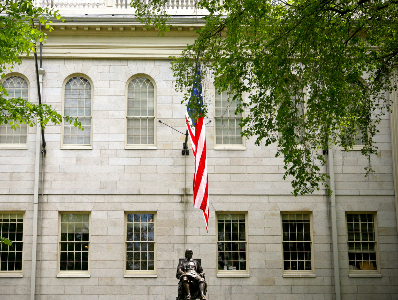 University Hall in the summer from the front view with the American flag above.