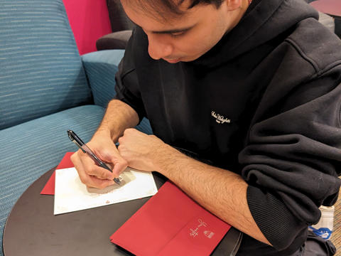 A first-year student in Thayer Hall writes a note of gratitude during a study break in his entryway.