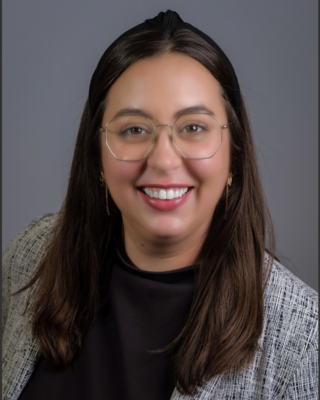 a smiling woman wearing glasses and a sweater