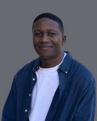 Man in a white shirt and blue button down looking at the camera and smiling