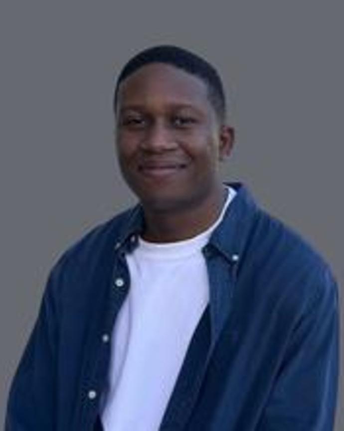 Man in a white shirt and blue button down looking at the camera and smiling
