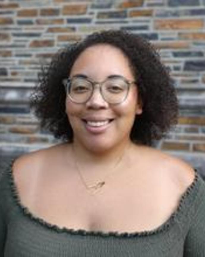 Black woman with shoulder length hair and glasses smiling at camera